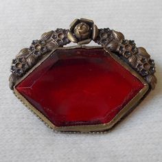 For your consideration we have a lovely lapel pin/brooch from the Victorian era. This pin is stunning in detail and color, done with bright red glass stone and bordered on the top by a floral design of brass. We believe this pin was upcylced from a possible shoe buckle. Measuring approximately 1.5" long and 1.25" tall, this is a great accessory for any dapper gent or well turned out woman.Shipping policies:If you choose to pay via Paypal, you must either be a verified buyer, or provide a confirm Vintage Red Lapel Pin For Gift, Red Vintage Lapel Pin For Gift, Vintage Red Lapel Pin As Gift, Red Vintage Lapel Pin As Gift, Antique Red Brooch Jewelry, Antique Red Brooch, Antique Red Brooch For Formal Occasions, Vintage Red Wedding Brooches, Vintage Red Brooches For Formal Occasions