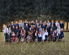 a large group of people posing for a photo in front of some trees and grass