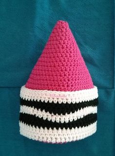 a crocheted pink hat with black and white stripes on the bottom, sitting on a blue background