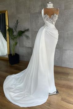 a white wedding dress on display in front of a mirror with a mannequin