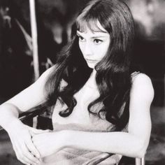 black and white photograph of a woman sitting on a chair with her hand on her hip