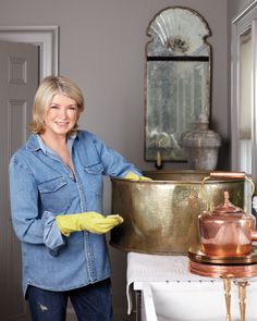 a woman in blue shirt and yellow gloves holding a pot