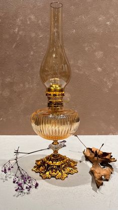 a glass vase sitting on top of a table next to dried leaves and an acorn