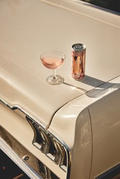 an old car with a glass of wine and a can of soda on the hood