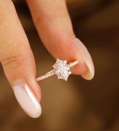 a woman's hand holding an engagement ring with a diamond in the middle and two diamonds on each side