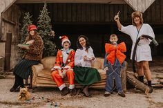 a group of people dressed up in costumes sitting on a couch with christmas trees behind them