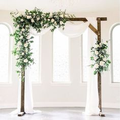 the wedding arch is decorated with white flowers and greenery for an elegant touch to the ceremony space