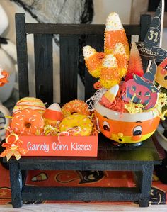 candy corn kisses in a pumpkin bowl on a wooden bench with halloween decorations around it