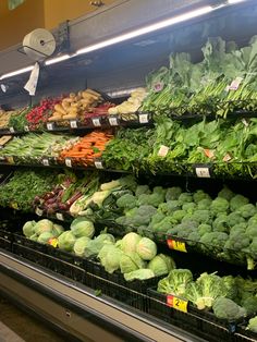 an assortment of vegetables are on display in a grocery store's produce section, including lettuce, broccoli, carrots and radishes