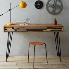 a desk with two stools and a clock on the wall