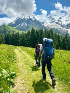 two people with backpacks walking up a trail in the mountains