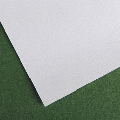 a close up view of a piece of white paper on green background with space for text