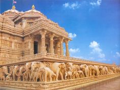 an intricately carved building with many elephants on the front and side walls, against a blue sky