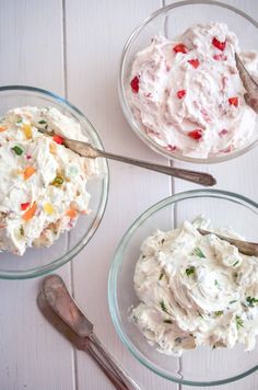 three glass bowls filled with food on top of a white wooden table next to utensils