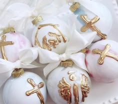 some white and gold ornaments are sitting on a plate with ribbon tied around the top