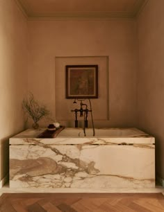 a bathroom with a marble tub and wooden flooring, framed artwork on the wall