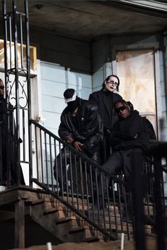 three people dressed in black are walking down the stairs