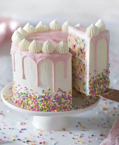 a white cake with pink frosting and sprinkles