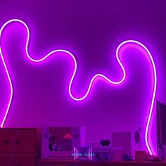 a purple neon light in the shape of a wave is lit up against a dark background