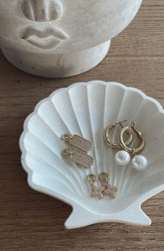 two pairs of earrings sitting on top of a white seashell next to each other