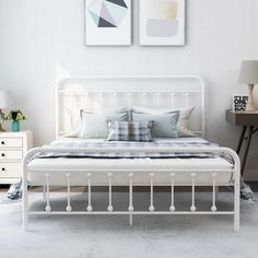 a white bed sitting in a bedroom next to two pictures on the wall above it