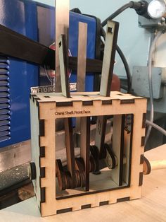 a wooden box with some metal parts in it on top of a workbench