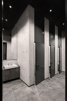 a bathroom with several stalls and sinks inside of it, all in black and white