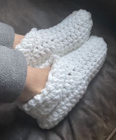 someone is wearing crocheted slippers with their feet propped up on the couch