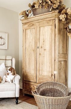 a dog sitting on top of a chair next to a wooden armoire in a living room