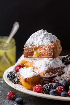 two powdered donuts stacked on top of each other with berries and blueberries