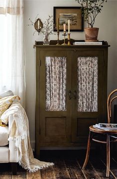 a living room with a white couch and green cabinet next to a window covered in curtains