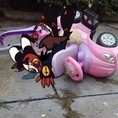 a pink scooter sitting on top of a sidewalk next to a toy car