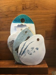 three ceramic plates sitting on top of a wooden shelf