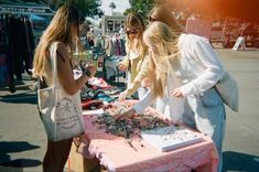 three women standing around a table with jewelry on it