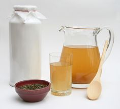 a pitcher and two glasses filled with liquid next to a bowl full of sugar, spoons and an empty jug