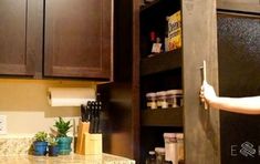 a woman is opening the door to a kitchen cabinet that has spices and other items on it