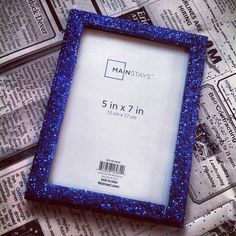 a blue frame sitting on top of a pile of newspaper with the words 5in x 7in in it