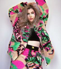 a woman with long hair wearing a colorful jacket and pants, posing for the camera