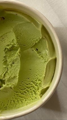 a bowl filled with green ice cream sitting on top of a white tablecloth covered table