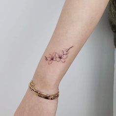 a woman's arm with a flower tattoo on the left side of her wrist