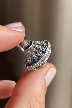 Antique Art Deco dinner ring, featuring tapering lines of old single cut diamonds with bright blue and angular calibré sapphires. It expresses highly architectural Egyptian Revival detail and delicate openwork. Made in a comfortable platinum setting with millegrain detail. Circa 1920. Ruby Cocktail Ring, Art Deco Platinum Ring Jewelry, Platinum Art Deco Ring Jewelry, Ceremonial Silver Diamond Ring, Collectible Art Deco Sapphire Ring, Art Deco Sapphire Ring With Diamond Cut, Ceremonial Silver Art Deco Jewelry, Art Deco Platinum Ring, Elegant Sterling Silver Dome Ring Collectible