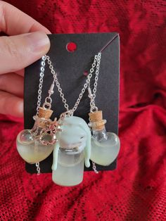 a pair of necklaces that have elephants in bottles attached to them on a chain