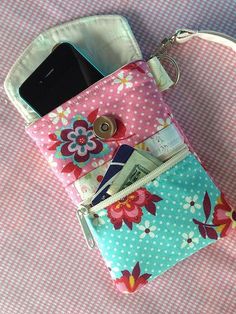 a cell phone and wallet sitting on top of a pink table cloth covered with polka dots