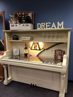 a white piano sitting in front of a blue wall with a light on it's side