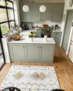 a kitchen with green cabinets and white counter tops, an area rug on the floor