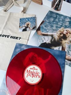 a red vinyl record sitting on top of a table next to pictures and a bag