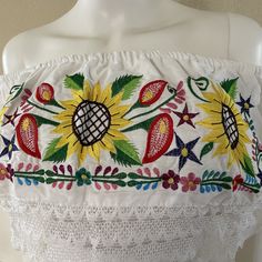 "Mexican Off shoulder elastic top with colorful sunflower embroidery. Made out of manta, 100% cotton. Color- Black/ Red and green floral embroidery. Please note: each piece is unique, the embroidery on the top and belt may be slightly different from the one pictured. Dimensions: Small Bust- 39\" Length- 20\" Medium Bust- 42\" Length- 20\" Made in Chiapas, Mexico. 🧺Care Instructions: We recommend hand washing, lay flat to dry. 📲Feel free to contact us with any questions you may have!  🛍More co Summer Festival Peasant Top With Embroidered Hem, Multicolor Embroidered Cotton Peasant Top, White Cotton Festival Peasant Top, White Cotton Peasant Top For Festival, Fitted Cotton Peasant Top With Embroidery, Peasant-style Embroidered Cotton Top For Beach, Summer Peasant Top With Multicolor Embroidery And Floral Print, Summer Embroidered Festival Tops, Bohemian Cotton Tops With Machine Embroidery