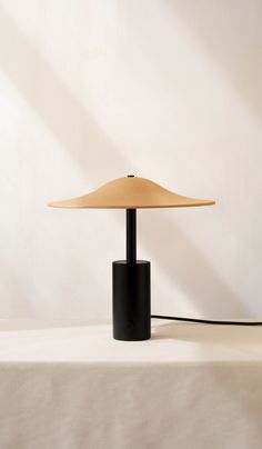 a table lamp sitting on top of a white cloth covered table next to a wall