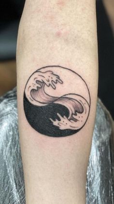 a black and white photo of a wave tattoo on the arm