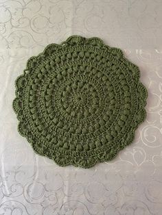 a green crocheted doily sitting on top of a white tablecloth